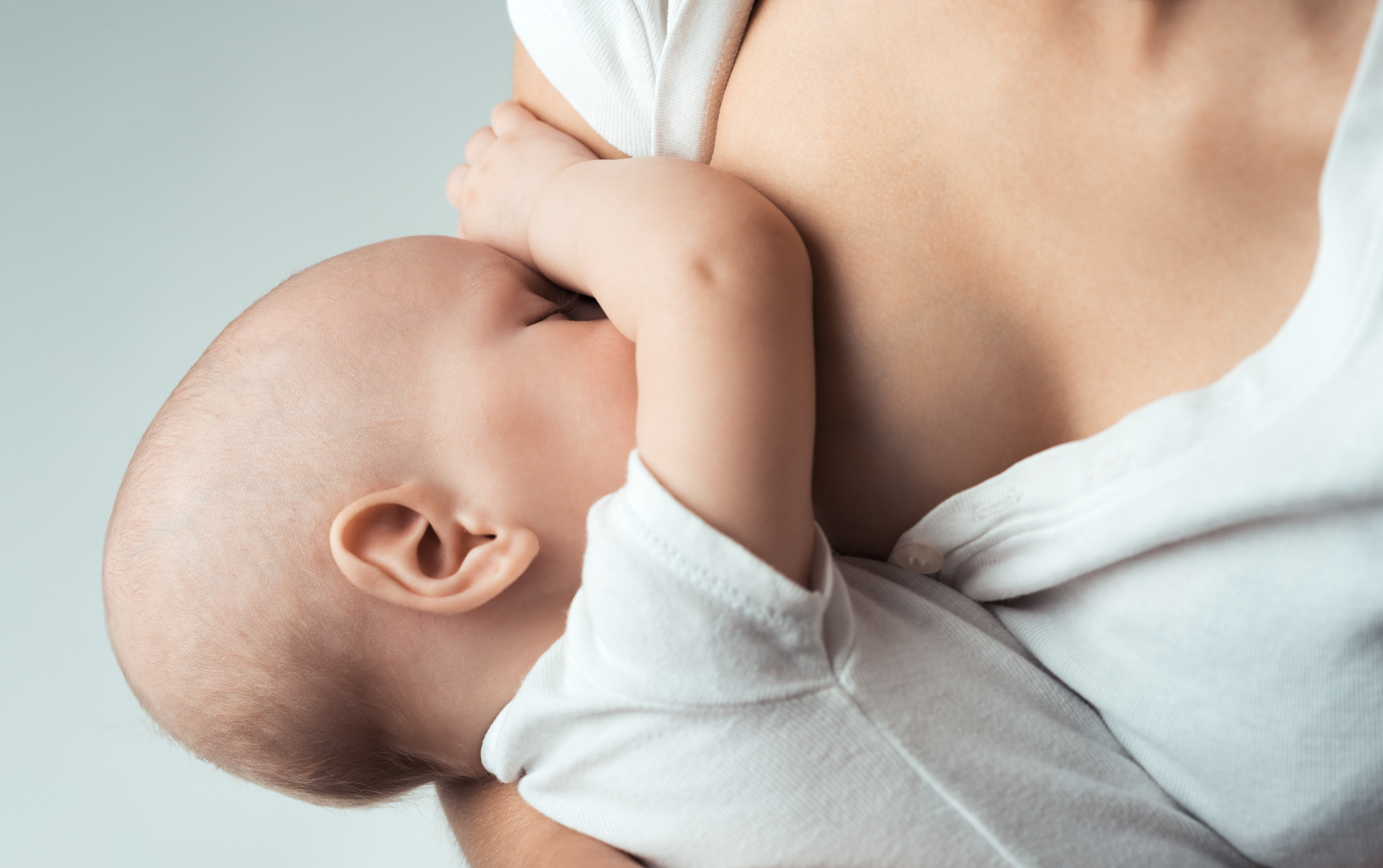 A mother breastfeeding her baby in a cozy home setting.